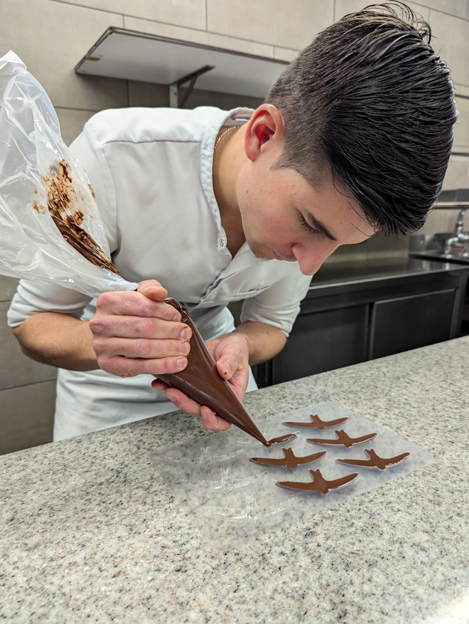 Le chocolatier, Guillaume Charlet, dans son laboratoire, rempli un moule de martinets